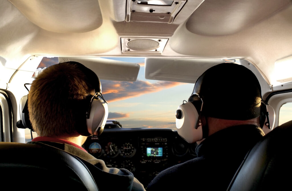 Pilot im Cockpit auf Rundflug im Sonnenuntergang