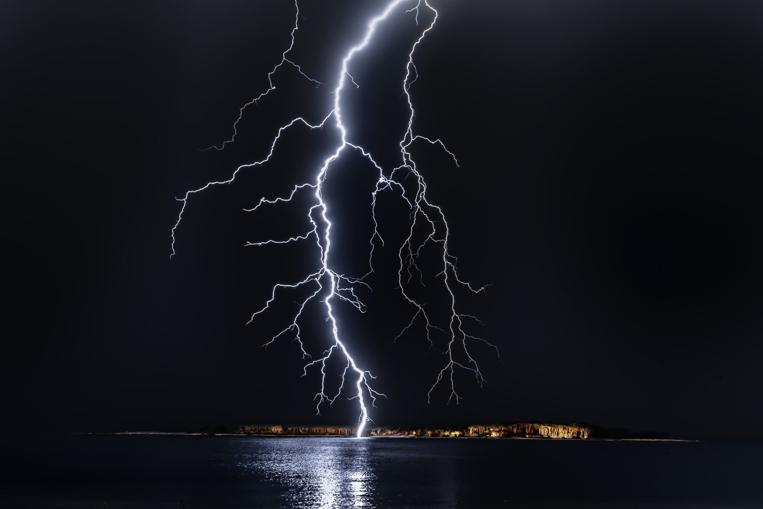 A bright bolt of lightning strikes an island, illuminating the dark ...